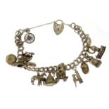 Silver charm bracelet with selection of mostly silver charms including a cow bell, windmill,