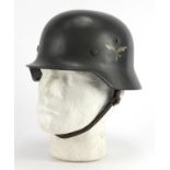 German Military interest tin helmet with decals and leather liner, impressed marks to the