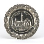 Iranian silver coloured metal plate, embossed with a church within a foliate border, 28cm in