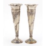 Pair of Victorian silver bud vases by William Comyns, each embossed with flowers and foliage, London
