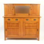 Arts & Crafts oak side cabinet with mirrored back, flanked by two cupboard doors above two drawers
