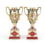 Pair of Vienna style porcelain trophy vases with twin handles, each decorated with panels of