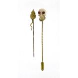 Two gold coloured metal tie pins comprising a mouse and carved coral skull with ruby eyes, the