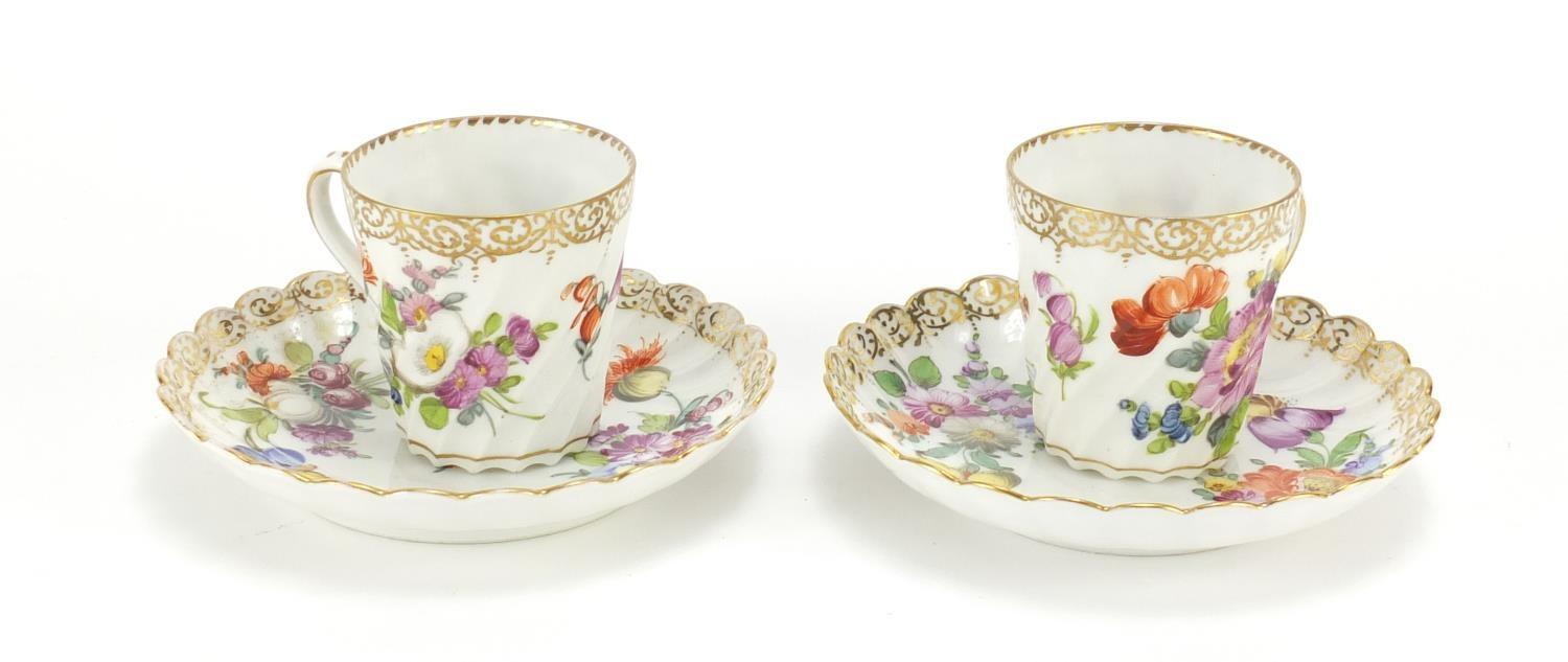 Two Dresden porcelain cups and saucers hand painted and gilded with flowers, the saucers, 13cm in