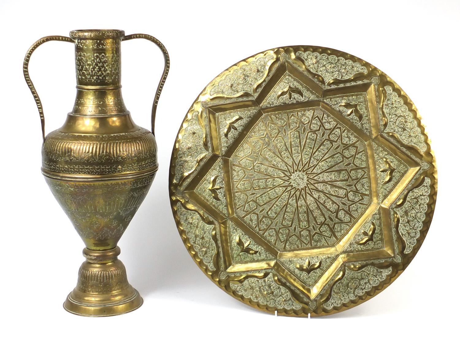 Large Indian brass twin handled vase and circular tray, both embossed and engraved with foliate