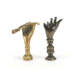 Two Victorian brass pipe tamper's in the form of a hand with a pipe and an open hand, the largest