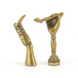 Two Victorian brass pipe tamper's in the form of a hand holding a pipe and a leg with boot, the