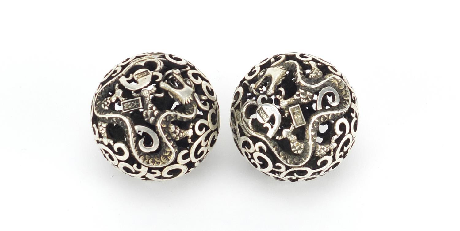 Pair of Chinese silver coloured metal stress balls, pierced with dragons and phoenixes, each 4.5cm