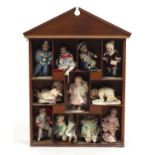 Eleven miniature Ashton Drake porcelain dolls on a display stand, the largest 18cm high : For