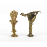 Two Victorian brass pipe tamper's in the form of a hand holding a pipe and a bust, each 5cm high :