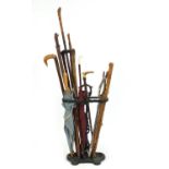 Victorian style cast iron stick stand with a selection of walking sticks, a horn handled riding crop