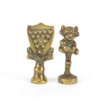 Two Victorian brass pipe tamper's in the form of a goblin and one and all crest, the largest 4.5cm