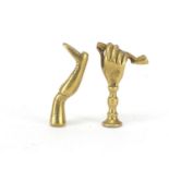 Two Victorian brass pipe tamper's in the form of a hand holding a pipe ad a leg with boot, the