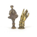 Two Victorian brass pipe tamper's in the form of seated tribesman and a open hand, the largest 5.5cm