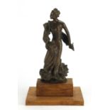Bronze figurine of an Art Nouveau female in a flowing dress, raised on a stepped wooden plinth base,