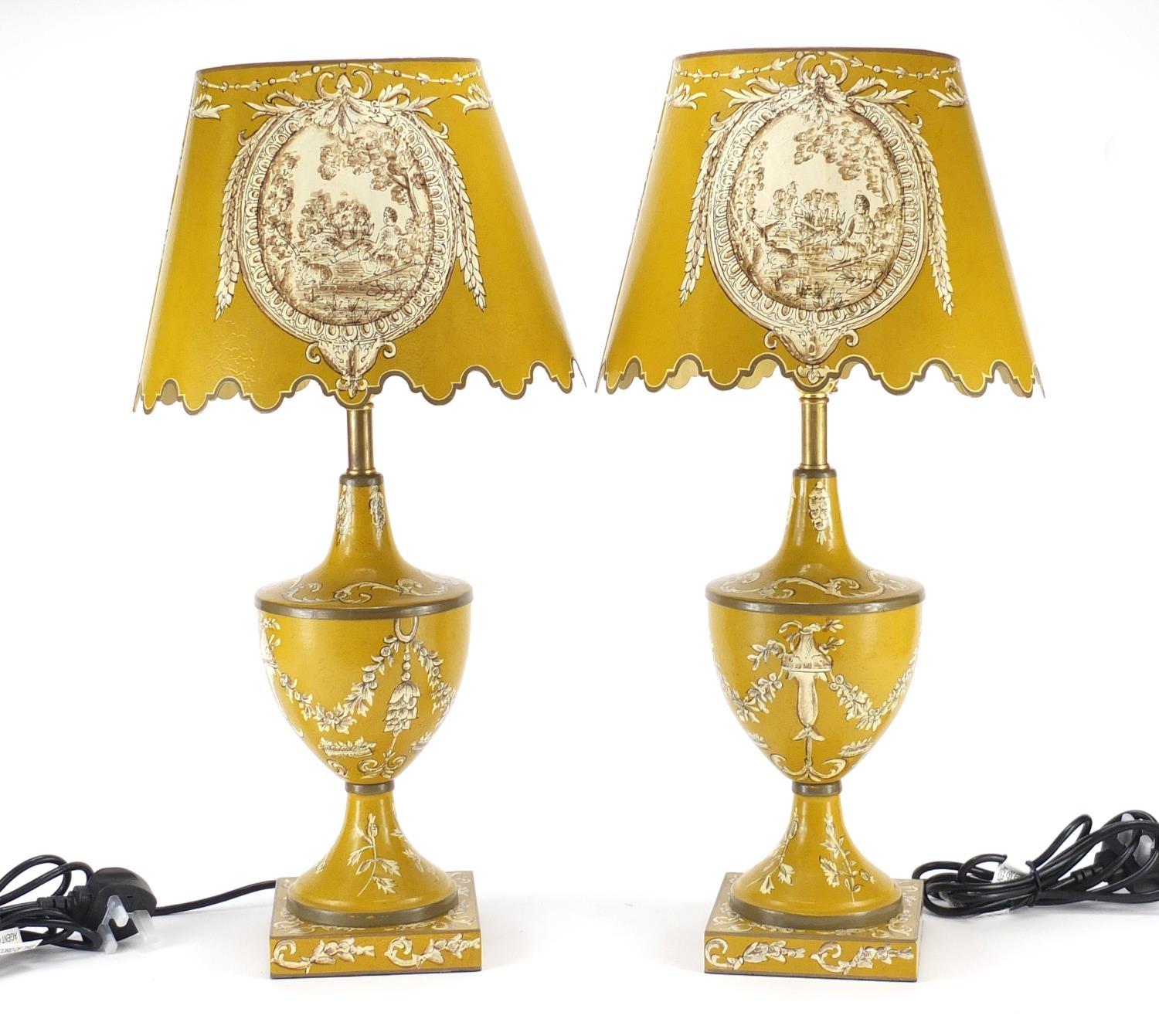 Pair of Toleware lamps with shades, each hand painted with panels of figures and foliate motifs,