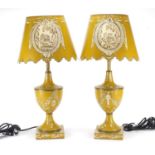 Pair of Toleware lamps with shades, each hand painted with panels of figures and foliate motifs,