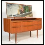 A vintage retro 20th Century teak dressing table chest of drawers raised on tapering legs. the