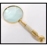 A 20th Century brass hand held magnifying glass with mother of pearl in lay to handle. Measures 25cm