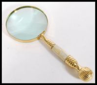 A 20th Century brass hand held magnifying glass with mother of pearl in lay to handle. Measures 25cm
