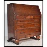 A 1940's Art Deco oak bureau being raised on ball feet with a bank of drawer under bureau atop