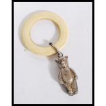 An early 20th Century teething ring with a silver teddy bear figure attached. Silver lion mark to