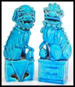 A pair of Oriental Chinese 20th Century ceramic temple lion dogs of Fu in blue raised on square