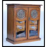 An early 20th Century Edwardian Art Nouveau table top oak smokers cabinet having twin glazed doors
