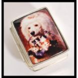 A silver pill / trinket box having an enamelled panel to the top depicting a dog and some kittens.
