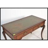 An early 20th Century mahogany Edwardian writing desk, flared top with inset green skiver over two
