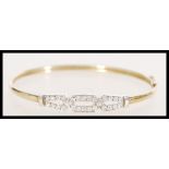 A stamped 9ct yellow gold bangle bracelet having a white gold section of crossover design set with