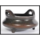 A 19th Century Chinese bronze censer ding bowl raised on tripod stubb feet with hoop handles. Four