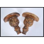 A pair of 20th Century carved wooden wall sconces / clock brackets having gilt floral detailing with