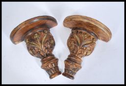 A pair of 20th Century carved wooden wall sconces / clock brackets having gilt floral detailing with