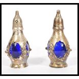 A pair of 20th Century silver plated condiments of bulbous form having pierced sides with blue glass