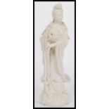 A large Chinese Blanc De Chine figurine of a Deity raised on scrolled base holding vase with