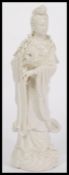 A large Chinese Blanc De Chine figurine of a Deity raised on scrolled base holding vase with