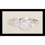 A hallmarked 9ct white gold cluster ring set with seven brilliant cut white stones. Hallmarked