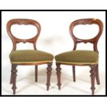 A pair of Victorian mahogany balloon back dining chairs being raised on turned legs with green