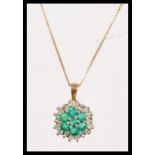 A hallmarked 9ct gold emerald and diamond cluster pendant necklace. Chain measures 18 inches,