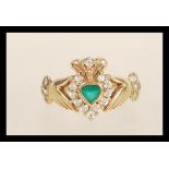 A hallmarked 9ct gold Claddagh ring set with a central green stone with white stone accents.
