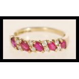 A hallmarked 9ct gold ruby and diamond ring set with alternating marquise cut rubies and round cut