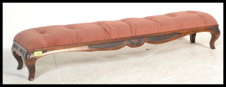 A Victorian 19th century long mahogany footstool being upholstered in a pink velour fabric over a