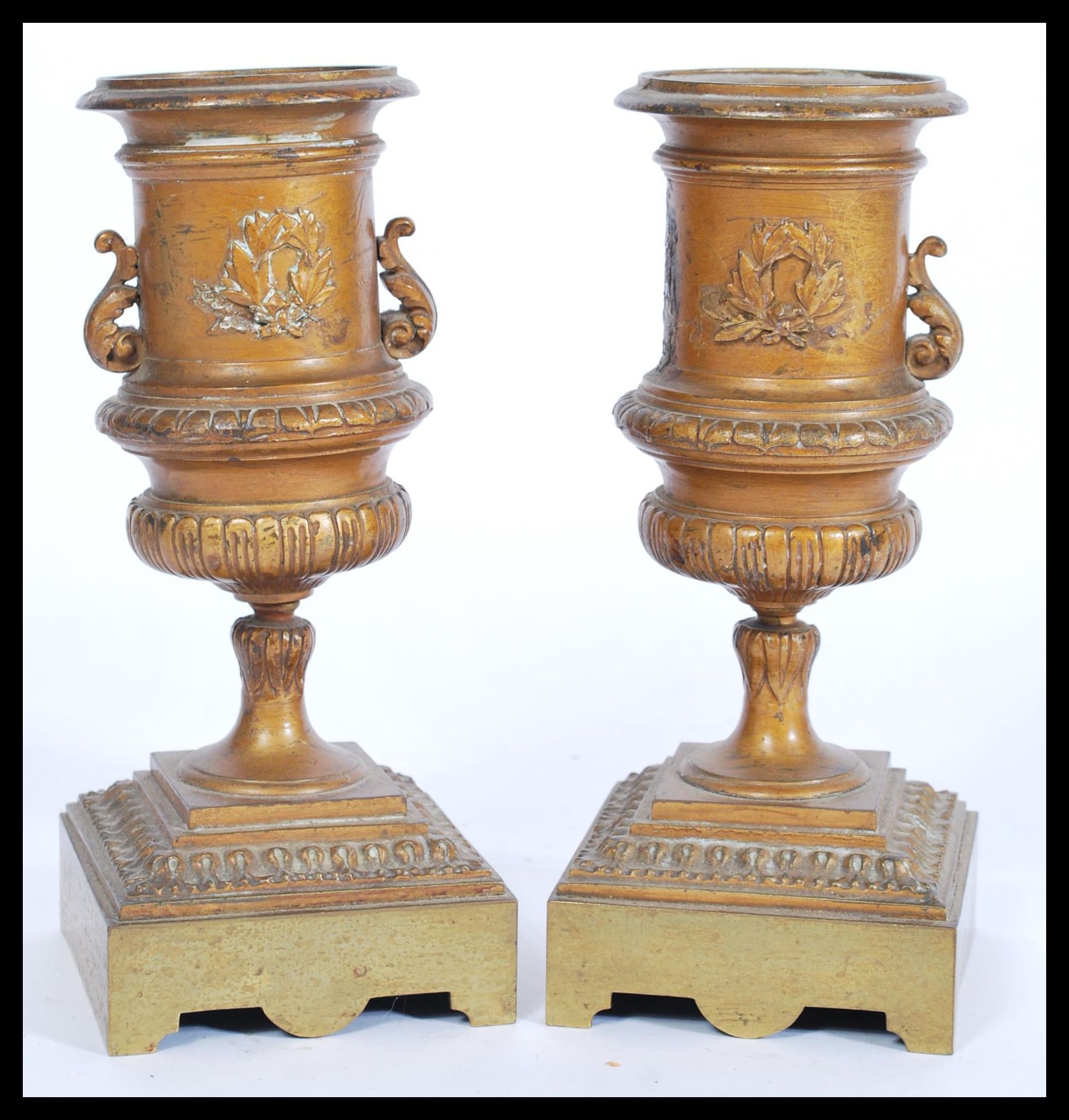 A pair of 19th century bronze urns raised on square bases with decorations of swags and ribbons with