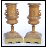 A pair of 19th century bronze urns raised on square bases with decorations of swags and ribbons with