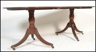 An Edwardian mahogany pedestal line inlaid dining table. Raised on reeded splayed leg twin columns