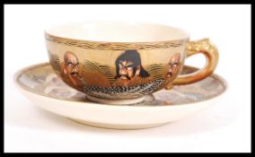A Japanese Meiji period Satsuma ware cup and saucer having decoration of Elders / Immortals and