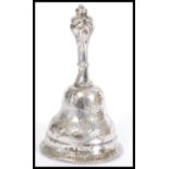 A silver bell having a bronze clanger, being engraved with floral detailing and decorative