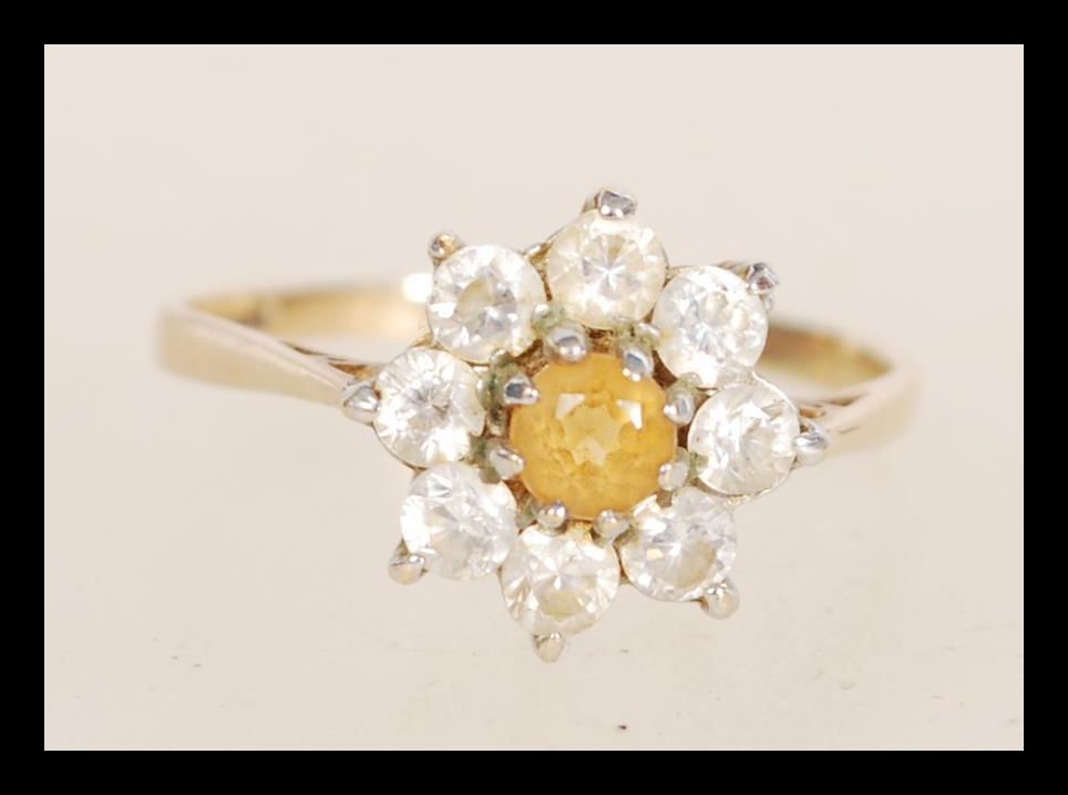 A hallmarked 9ct gold ring set with a central yellow stone flanked by white stones. Hallmarked