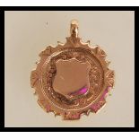 A hallmarked 9ct gold medal pendant having an unmarked central armorial cartouche panel and